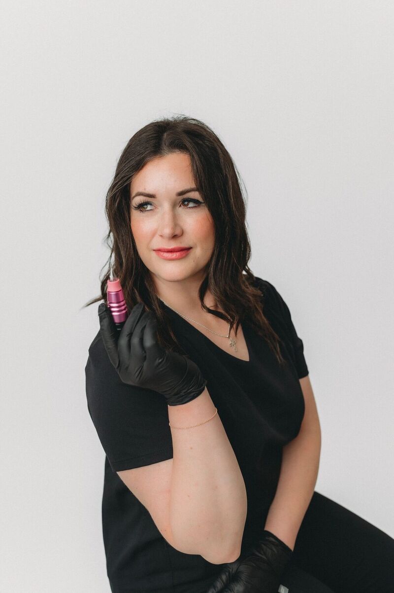Rachel Rife in a black top, holding a permanent makeup machine